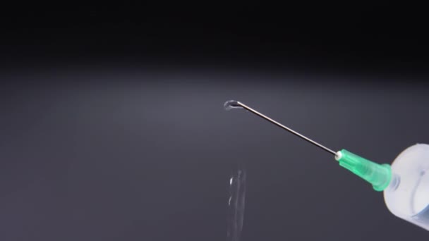 Une aiguille libère une goutte de liquide transparent 