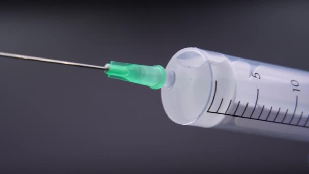 Une aiguille libère une goutte de liquide transparent 