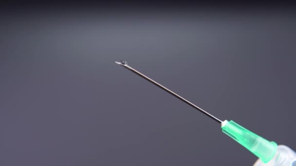 Une aiguille libère une goutte de liquide transparent 