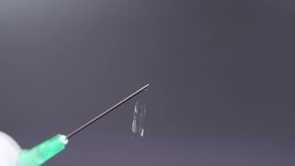 Une aiguille libère une goutte de liquide transparent 