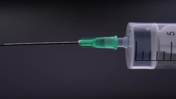 Une aiguille libère une goutte de liquide transparent 