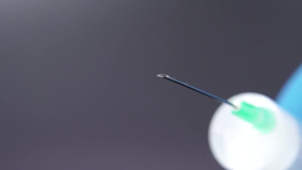 Une aiguille libère une goutte de liquide transparent 