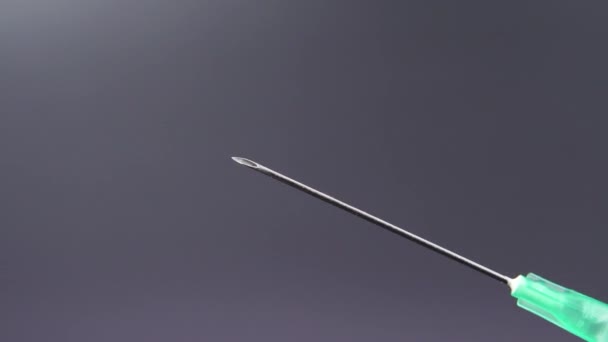 Une aiguille libère une goutte de liquide transparent 