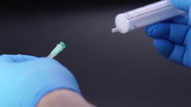 Doktor şırıngaya bir iğne takıyor.