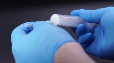 Doktor şırıngaya bir iğne takıyor.