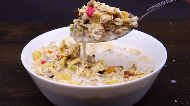 Stirring spoon of muesli with milk in a white bowl closeup — Stock Video