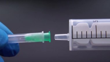 Doktor şırıngaya bir iğne takıyor.