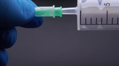 Doktor şırıngaya bir iğne takıyor.