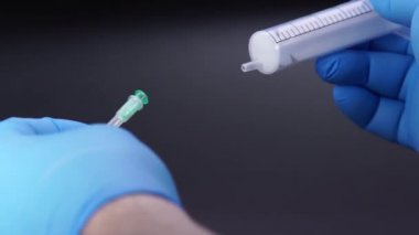 Doktor şırıngaya bir iğne takıyor.