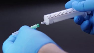 Doktor şırıngaya bir iğne takıyor.