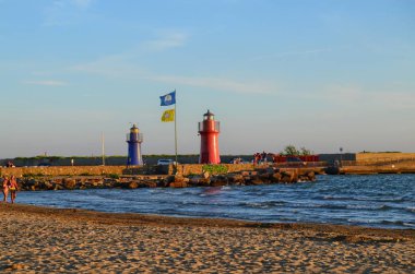 Castiglione della Pescaia, Toskana, İtalya, sahilde günbatımı 26 Ağustos 2014 burada 20:30. Kırmızı ve mavi deniz feneri iskelede kanıt.