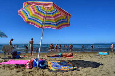 Castiglione della Pescaia, Toskana, İtalya 17 Ağustos 2014 11:00. Turistler şemsiye ve şezlonglar ile ince kumlu plaj.