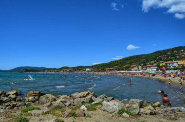 Castiglione della Pescaia, Toskana, İtalya 17 Ağustos 2014 11:00. Turistler şemsiye ve şezlonglar ile ince kumlu plaj.