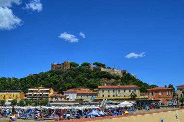 Castiglione della Pescaia, Toskana, İtalya 18 Ağustos 2014, 5 pm. 00 aşağıdan, köy ve kale tepe standları üst doğru görüntülemek.