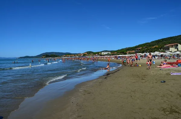 Castiglione della Pescaia, Toskana, İtalya 17 Ağustos 2014 11:00. Turistler şemsiye ve şezlonglar ile ince kumlu plaj.