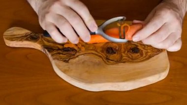 Hangi beyaz adamın kollarından erkek kabuğu sebzeli üç Havuç soyulmuş olan zaman atlamalı. Doğrama kurulu zeytin ahşap, kiraz tablo olarak.