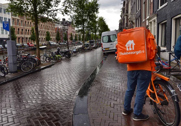 Amsterdam, Hollanda, Ağustos 2019. Thuisbezorgd 'dan bir işçi, ev