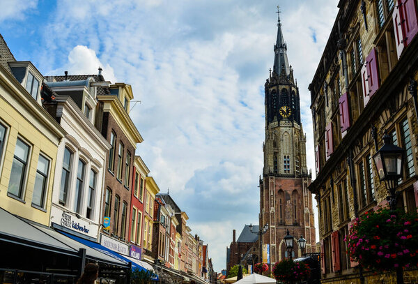 Delft, the Netherlands, August 2019. The bell tower of the new church, in Dutch Nieuwe Kerk. Characterized by red bricks, with its height and grandeur it stands out immediately. Blue sky, white clouds