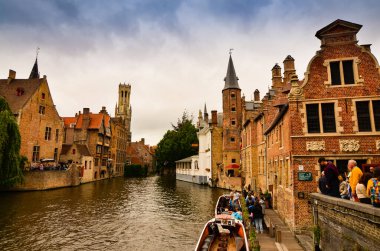 Bruges, Flanders Belçika. Ağustos 2019. Rozenhoedkaai, turistler tarafından en çok sevilen tarihi merkezin bir simgesidir: Söğüt ağacı ve çan kulesi ile evin etrafında kıvrılan kanal..