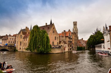 Bruges, Flanders Belçika. Ağustos 2019. Rozenhoedkaai, turistler tarafından en çok sevilen tarihi merkezin bir simgesidir: Söğüt ağacı ve çan kulesi ile evin etrafında kıvrılan kanal..