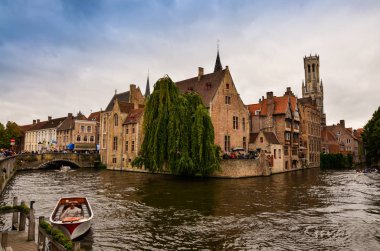 Bruges, Flanders Belçika. Ağustos 2019. Rozenhoedkaai, turistler tarafından en çok sevilen tarihi merkezin bir simgesidir: Söğüt ağacı ve çan kulesi ile evin etrafında kıvrılan kanal..