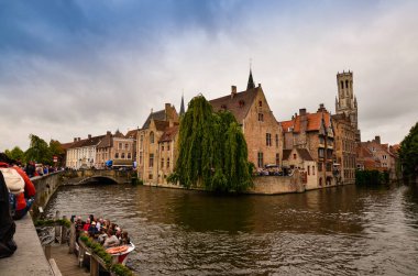Bruges, Flanders Belçika. Ağustos 2019. Rozenhoedkaai, turistler tarafından en çok sevilen tarihi merkezin bir simgesidir: Söğüt ağacı ve çan kulesi ile evin etrafında kıvrılan kanal..
