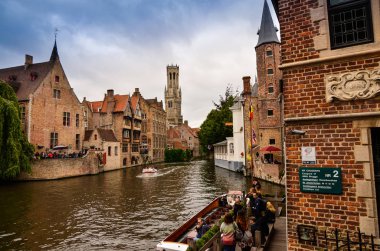 Bruges, Flanders Belçika. Ağustos 2019. Rozenhoedkaai, turistler tarafından en çok sevilen tarihi merkezin bir simgesidir: Söğüt ağacı ve çan kulesi ile evin etrafında kıvrılan kanal..