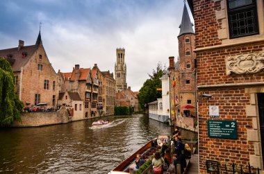 Bruges, Flanders Belçika. Ağustos 2019. Rozenhoedkaai, turistler tarafından en çok sevilen tarihi merkezin bir simgesidir: Söğüt ağacı ve çan kulesi ile evin etrafında kıvrılan kanal..