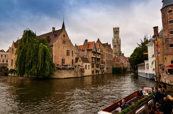 Bruges, Flanders Belçika. Ağustos 2019. Rozenhoedkaai, turistler tarafından en çok sevilen tarihi merkezin bir simgesidir: Söğüt ağacı ve çan kulesi ile evin etrafında kıvrılan kanal..