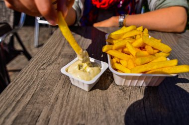 Bruges, Belçika, Ağustos 2019. Turistik Markt Meydanı 'na bakan bir kızartma dükkanı. Beyaz bir kadın tartar soslu cipslerinin tadını çıkarıyor. Patates cipsine odaklan.