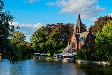 Bruges, Belçika. Ağustos 2019. Göl ve minnewater parkı en romantik yerdir. Kırmızı tuğladan kale ve yeşil yapraklı büyük ağaçların yansıdığı su kütlesi..