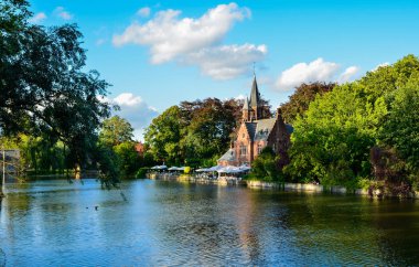 Bruges, Belçika. Ağustos 2019. Göl ve minnewater parkı en romantik yerdir. Kırmızı tuğladan kale ve yeşil yapraklı büyük ağaçların yansıdığı su kütlesi..