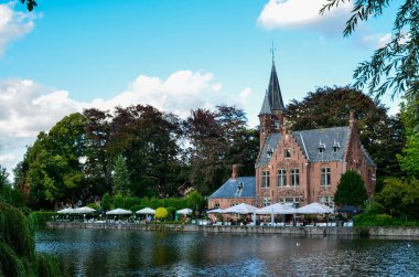 Bruges, Belçika. Ağustos 2019. Göl ve minnewater parkı en romantik yerdir. Kırmızı tuğladan kale ve yeşil yapraklı büyük ağaçların yansıdığı su kütlesi..