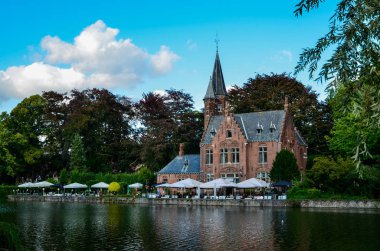 Bruges, Belçika. Ağustos 2019. Göl ve minnewater parkı en romantik yerdir. Kırmızı tuğladan kale ve yeşil yapraklı büyük ağaçların yansıdığı su kütlesi..
