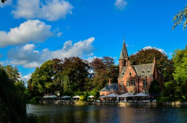Bruges, Belçika. Ağustos 2019. Göl ve minnewater parkı en romantik yerdir. Kırmızı tuğladan kale ve yeşil yapraklı büyük ağaçların yansıdığı su kütlesi..