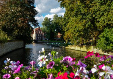 Bruges, Belçika. Ağustos 2019. Sashuis kilidiyle köprüden tarihi merkeze doğru bakın. Bir ekici, gözü şehre yönelten kanalı çerçeveler. Yanlarda büyük yeşil yapraklar var..