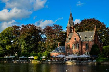 Bruges, Belçika. Ağustos 2019. Göl ve minnewater parkı en romantik yerdir. Kırmızı tuğladan kale ve yeşil yapraklı büyük ağaçların yansıdığı su kütlesi..