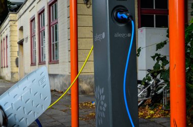 Bruges, Belçika. Ağustos 2019. Elektrikli arabalar için bir şarj istasyonu: bir mavi ve bir sarı kablo sırasıyla bir hyundai ve elektrikle çalışan bir Volkswagen 'e bağlıdır.