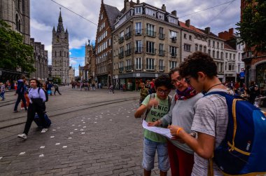 Gent, Belçika, Ağustos 2019. İki çocuk anneleriyle birlikte turist haritasına bakıyorlar. Arkalarında Aziz Niklas kilisesi ve çan kulesi Beffroi var..