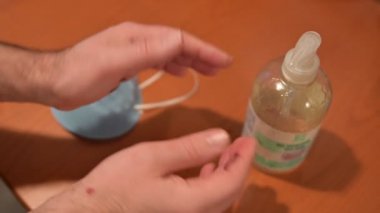 Coronavirus: tokalaşmanın ardında bulaşıcı hastalık riski. Beyaz bir adamın avucundaki yazı, adama nasıl saldırdığını vurguluyor. Masaya, jöle ve maske. Jöleyi bir eline al ve ovala.