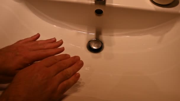 コロナウイルス。ウイルスの危険性の概念的なイメージ:白人男性の手の手のひらに碑文は、それが人を攻撃する方法を強調しています。背景には、洗浄と洗浄のためのシンク. — ストック動画