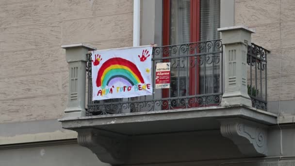 Torino, Piemonte, Italia. Marzo 2020. Pandemia di coronavirus. Sulle facciate delle case appendere le lenzuola con il disegno dell'arcobaleno e il messaggio "tutto andrà bene ". — Video Stock