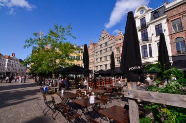 Gent, Belçika. Ağustos 2019. Merkezin tarihi meydanı Korenmarkt 'ta, sokakta masaları ve şemsiyeleri olan barlar ve restoranlar var. İnsanlar masalarda ve yürüyorlar..