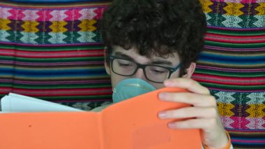 Yatalak beyaz bir çocuk mavi koruyucu bir maske takıyor. O, turuncu kaplı defterini inceliyor. Koronavirüs pandemik karantinası sırasında ev çalışması kavramı.