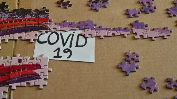 トリノ、ピエモンテ、イタリア。2020年3月。コロナウイルスのパンデミックの概念的なイメージ。隔離時間を過ごすためにパズル。白人の手で置かれているタイルは、 COVID-19の書き込みをカバーしています. — ストック動画