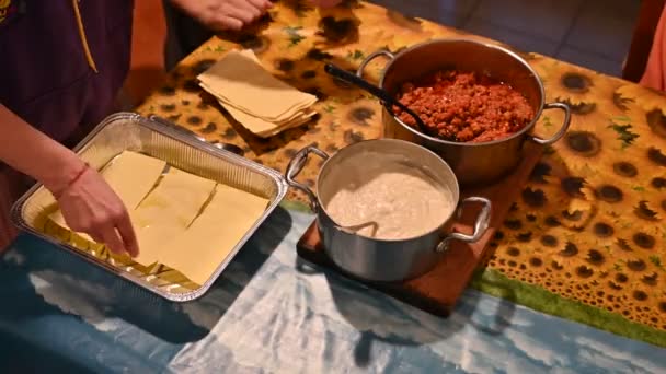 Домашня підготовка лазанью. Руки кавказької жінки кладуть у сковороду листки тутового тіста.. — стокове відео