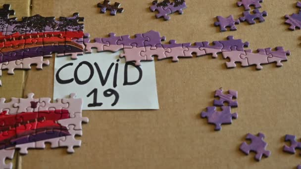 トリノ、ピエモンテ、イタリア。2020年3月。コロナウイルスのパンデミックの概念的なイメージ。隔離時間を過ごすためにパズル。白人の手で置かれているタイルは、 COVID-19の書き込みをカバーしています. — ストック動画