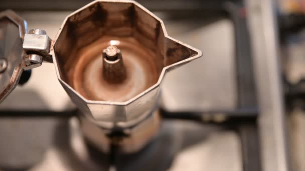Kávét főzök a fazékkal. Közelkép a kávéfőző kiömléséről. A homályos háttérben látható egy kéz, ami működteti a gázkart, és a kék láng begyullad.. — Stock videók