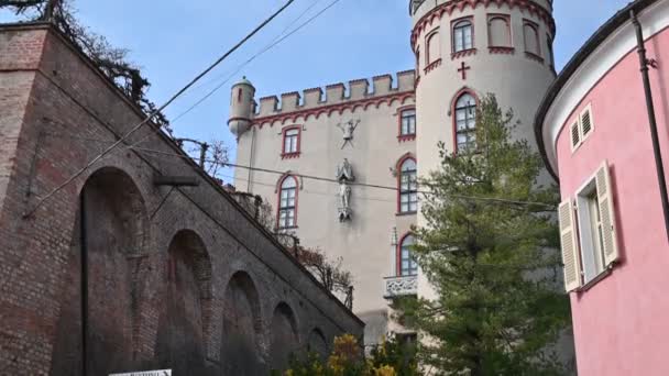 Costigliole d 'Asti, Piedmont, İtalya. Mart 2020. Kalenin yan tarafında eğik bir görüntü: kule ve kırmızı bitişler vurgulanır. Çevredeki evlere göre şekli göze çarpıyor. Mavi gökyüzü — Stok video