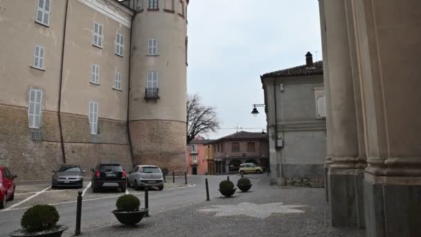 Costigliole d 'Asti, Piedmont, İtalya. Mart 2020. Kalenin kırmızı uçlu kulelerinden birinde eğik hareketli görüntü. Birkaç araba park etmiş.. — Stok video